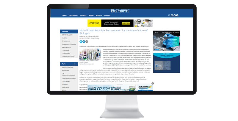 A computer screen displays a BioPharm article on microbial fermentation in biologics. The layout includes text, images, and navigation menus.