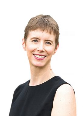 A smiling person with short hair in a sleeveless black top on a white background. No recognizable landmarks or historical buildings are present.